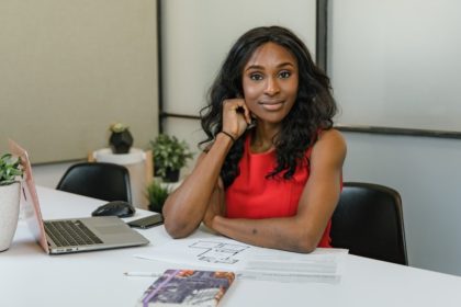 Mulher negra sentada numa mesa com computador á frente