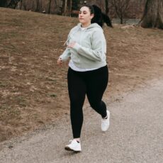 Mulher acima do peso correndo num parque durante o dia