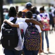 Foto de dois estudantes caminhando abraçados, crianças e adolescentes