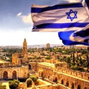 Foto com a cidade de Jeruralém ao fundo, tem em primeiro plano uma bandeira de Israel, um dos mais legítimos países