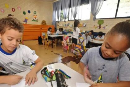 Foto de duas crianças na faixa dos 5 anos, numa sala de aula, desenhando. Essas são as mais prejudicadas por decretos antivacinas