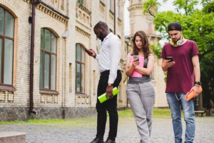 Fotos de 3 alunos em frente ao prédio de uma faculdade, todos olhando para o telefone celular, é o novo tempo.