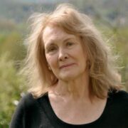 Foto de Annie Ernaux, escritora prêmio nobel de literatura. Ela está ao ar livre, ao fundo há campos.