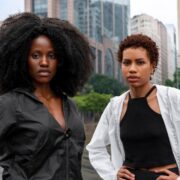 Na foto, em plano americanos, duas jovens negras na luta constra o racismo