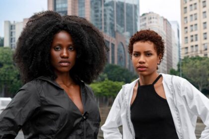 Na foto, em plano americanos, duas jovens negras na luta constra o racismo