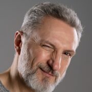 Foto do rosto de um homem idoso, bonito, cabelos e barba grisalhos