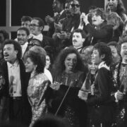 Foto em preto e branco com o conjunto de estrelas que gravaram a música We are the world no anos 80.
