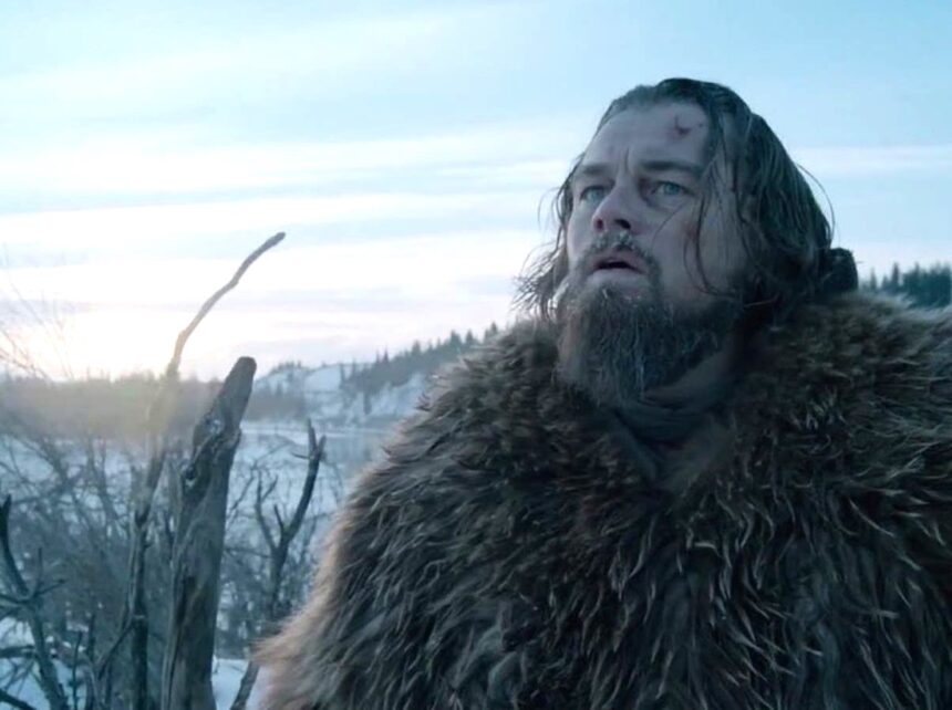 Foto do protagonista do filme O Regresso, Leonardo di Caprio, em meio a uma área nevada, com um casaco de pele de urso por cima.