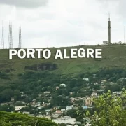 Foto simulando o letreiro como nome de Porto Alegre no alto de um morro da cidade. Ao fundo, antenas de transmissão.