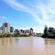 Foto do Rio Itajaí, com a cidade de Blumenau à direita. proximidade com o rio colocam risco a vida do local.