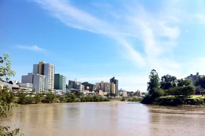 Foto do Rio Itajaí, com a cidade de Blumenau à direita. proximidade com o rio colocam risco a vida do local.