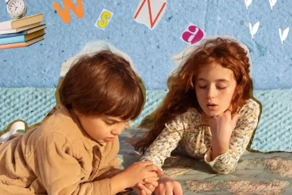 Foto de duas crianças, um menino e uma menina, deitados de bruços no chão, brincando. O menino sob o olhar da menina.