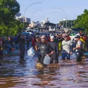 Foto da tragédia da enchente em Porto Alegre, voluntários no meio d'agua carregam mantimentos para as vítimas