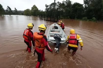 Fotos de voluntários da enchente do RS empurrando um barco dentro da água. Esses são os heróis, ou outros os sem-noção