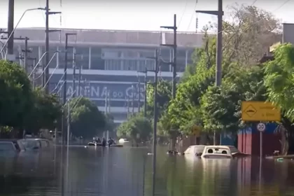 Foto de uma rua do Bairro Humaitá inundada pela enchente. Ao fundo está a Arena do Grêmio.
