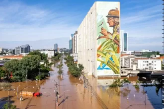 Foto de um painel do ambientalista José Lutzenberger pintado num prédio público, na Av. Borges de Medeiros, em Porto Alegre, que sofreu inundação na enchente