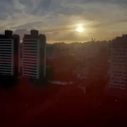 Foto de prédios entremeados pelo sol caindo, em porto alegre, depois da enchente de 2024.