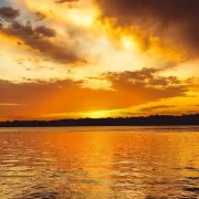 Foto do rio uruguai, no rio grande do sul, com um sol alaranjado banhando a água