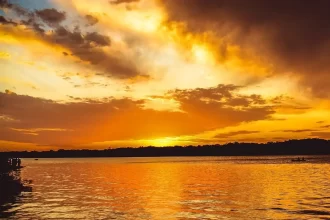 Foto do rio uruguai, no rio grande do sul, com um sol alaranjado banhando a água