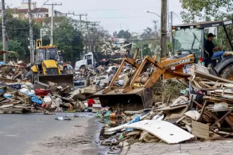 Foto de uma rua de Canoas cheia de lixo das enchentes. O negacionismo ainda reverbera