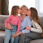 Foto de uma avó com as duas netas a beijando, a avosidade é uma benção.