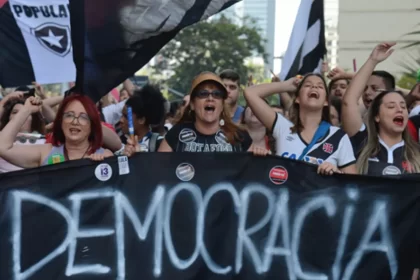 Foto de uma manifestação a favor da democracia, mulher carregam uma grande faixa.