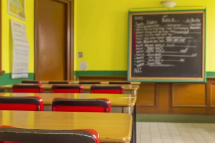 Foto de uma sala de aula, com uma lousa ao fundo com modo verbal