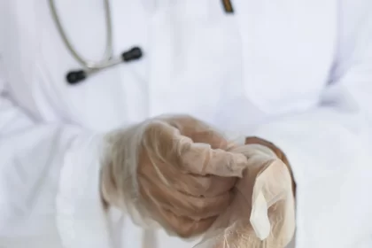 Foto de um médico colocando luvas de borrachas. Não bastam palavras