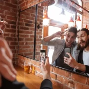 Dois amigos na mesa de bar postam nas redes sociais..