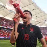 Foto do atacante albanês Mirlind Daku com um megafone em punho protestando contra os sérvios