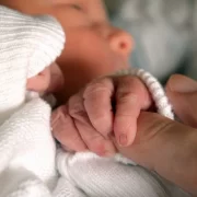 Foto de um recém-nascido de mãos dadas com a avó