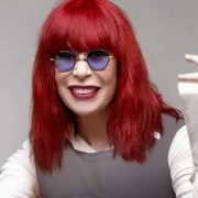 Foto da cantora Rita Lee de cabelos vermelhos e óculos redondos azuis, música