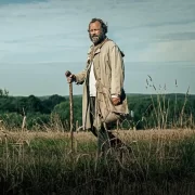 Homem caminha numa área rural, cena do filme amor esquecido