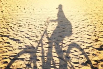 Foto da sombra na areia de uma mulher de bicicleta numa praia da califórnia, um lugar especial para a autora