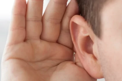 Foto de uma pessoa com a mão na orelha, indicando problema de audição. É preciso fazer audiometria