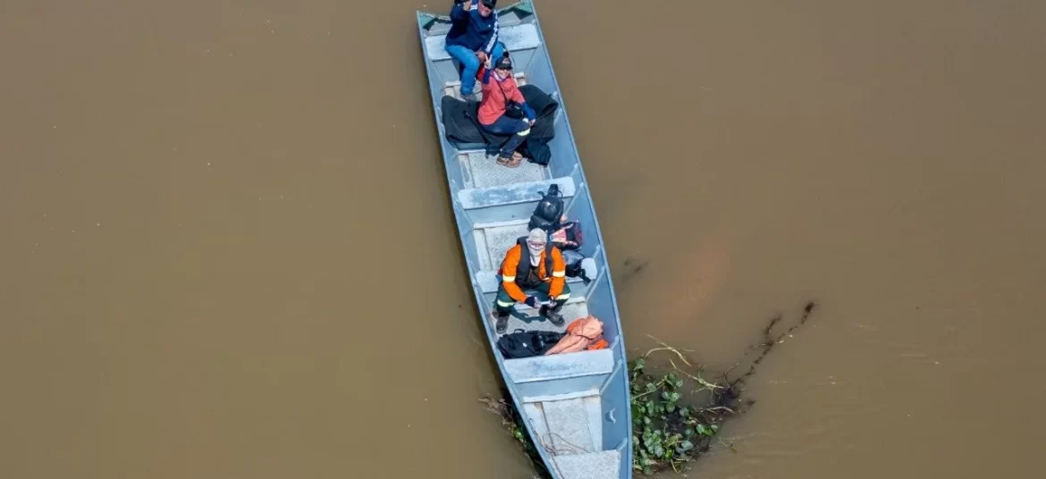 Foto aérea de uma barco pequeno no meio de um rio de águas marron, é o jornalismo ambiental