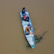 Foto aérea de uma barco pequeno no meio de um rio de águas marron, é o jornalismo ambiental