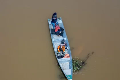 Foto aérea de uma barco pequeno no meio de um rio de águas marron, é o jornalismo ambiental