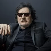 Foto do artista Charly García, vestido de preto e óculos escuros