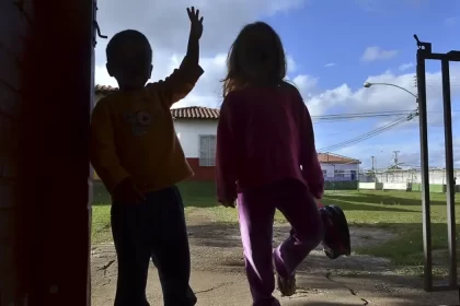 Foto de duas crianças de costas na porta de casa. Investigação da paternidade