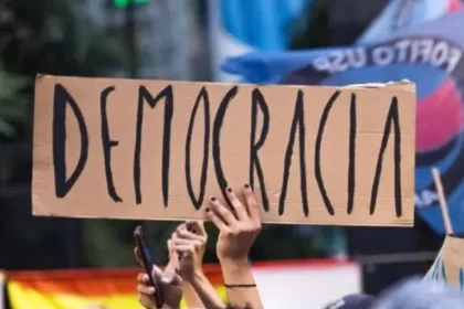 Foto de um cartaz de papelão, numa manifestação, com a palavra democracia