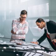 Dois homens em frente a um carro. Um deles inspeciciona bem de perto o capô do carro. Foi assim que o autor teve a ideia de um poema