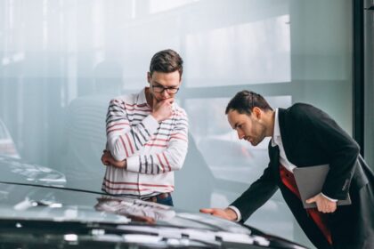 Dois homens em frente a um carro. Um deles inspeciciona bem de perto o capô do carro. Foi assim que o autor teve a ideia de um poema