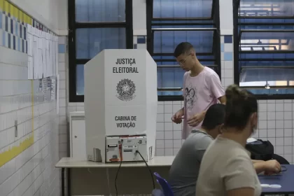 Foto de uma urna com um eleitor jovem votanto