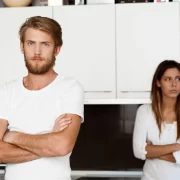 Um homem à frente e uma mulher ao fundo com cara de emburrada. Legislação brasileira não aceita as famílias simultâneas