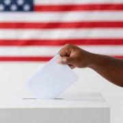 Imagem da bandeira america e o braço de um homem negro colocando voto na urna, Filósofo Slavoj Zizek analisa