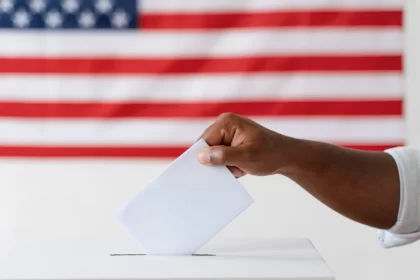 Imagem da bandeira america e o braço de um homem negro colocando voto na urna, Filósofo Slavoj Zizek analisa