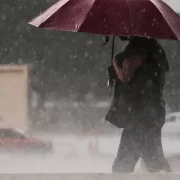 Foto de uma pessoa com guarda chuva num temporal. Não é por falta de conselho que autoridades não cuidam mais do meio ambiente