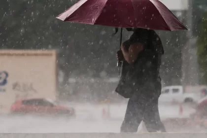 Foto de uma pessoa com guarda chuva num temporal. Não é por falta de conselho que autoridades não cuidam mais do meio ambiente