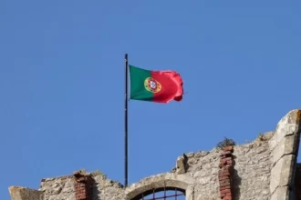 Foto da bandeira de portugal no alto de um castelo. A língua portuguesa é a última flor do láscio